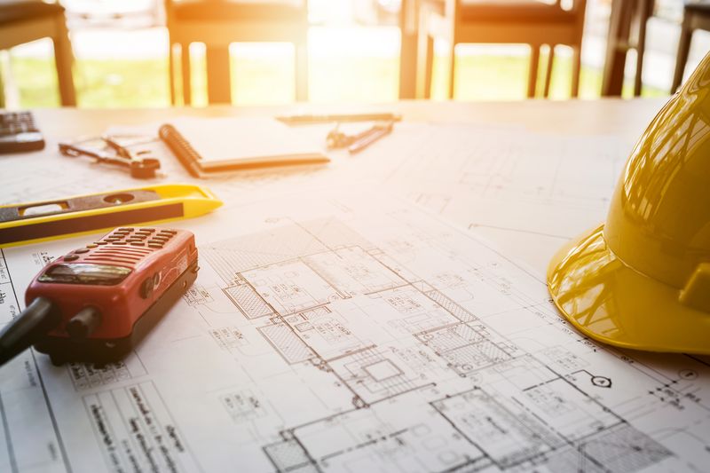 Architectural blueprints, hard hat and measuring tools on a planning desk