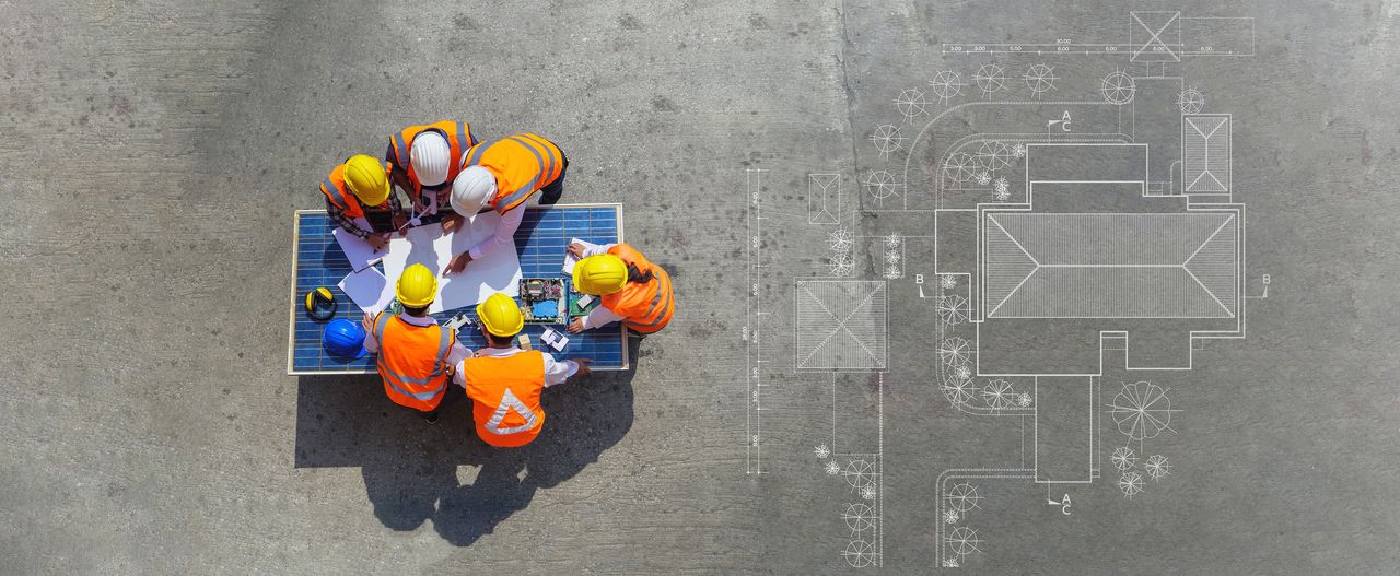 Construction project team reviewing plans on site, aerial view